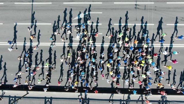 Large group of athletes running city marathon, aerial view, running shadows