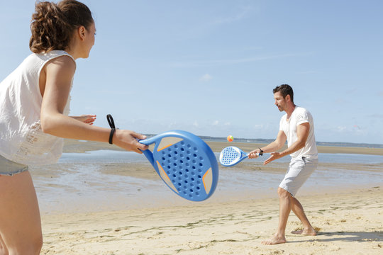couple playing tennis on the beach