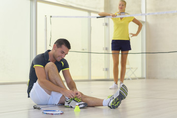 woman waiting at badminton net while man ties his shoelaces