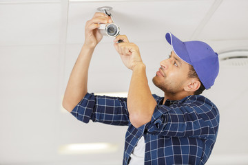 technician installing surveillance camera in the house carport