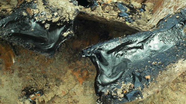 Toxic tar asphalt chemical in detail and closeup clay. Former dump waste, effects nature from contaminated soil and water with chemicals and oil, black bitumen refined synthetic material