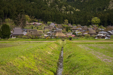 Fototapeta na wymiar Narrow water canal for irrigating fields runs to small Japanese farming town in the mountains