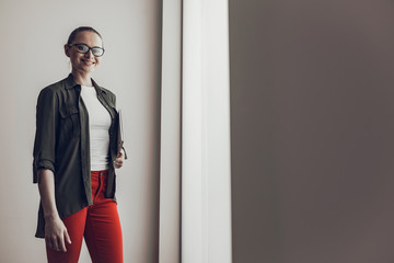 Happy female coworker in casual wear is holding laptop