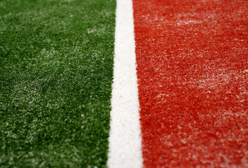 White line on green and red artificial turf, sand infill, selective view perspective.