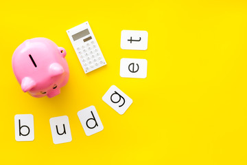 Business and budget concept with piggy bank and calculator on yellow office background top view