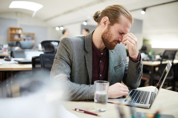 Side view portrait of exhausted businessman working in open space office