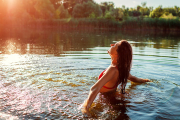 Young woman in bikini playing in water and making splash. Summer vacation