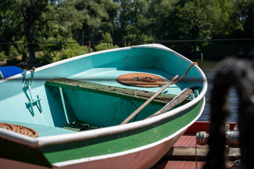 Ocean blue paddle boat with green and coral hull and ropes on coral deck of a gasoline ship