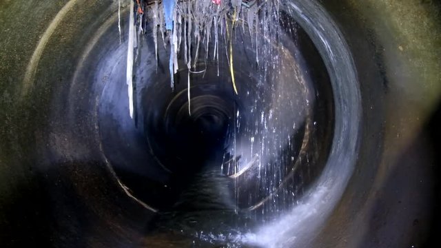 Dark underground sewer round concrete tunnel. Industrial sewage flowing throw sewer pipe