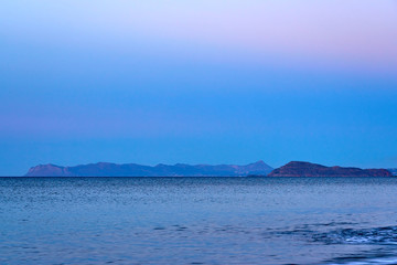                               Colorful foggy sunset over the sea with mountains on a background.