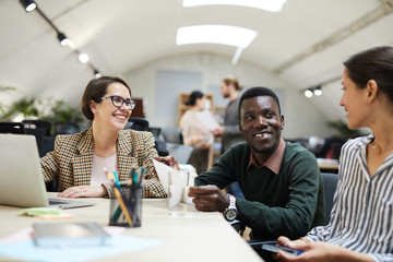 Multi-ethnic group of people smiling happily while working together in office, copy space