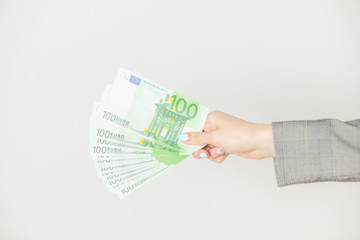 Female hands holding euro banknotes on a white background.