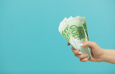 Female hands holding euro banknotes on a blue background.