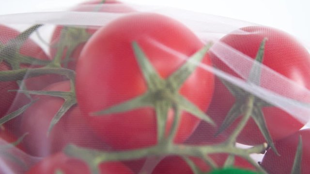A ripe branch of cherry tomato lies in a reusable reuse bag on an isolated white background. to deal with disposable plastic bags