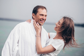 Fototapeta premium A young girl and a grown man.Couple in love on the shore in cloudy weather.A loving adult couple.A couple in a white coat.Couple in love