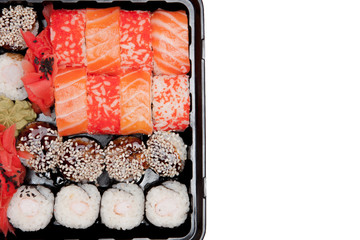 Big sushi set ib black plastic box on white background, top view close up, copy space