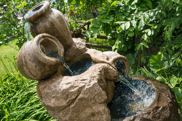 Mini fountain or waterfall of jugs in outdoors, nature, greenery. look beautiful and suitable for...