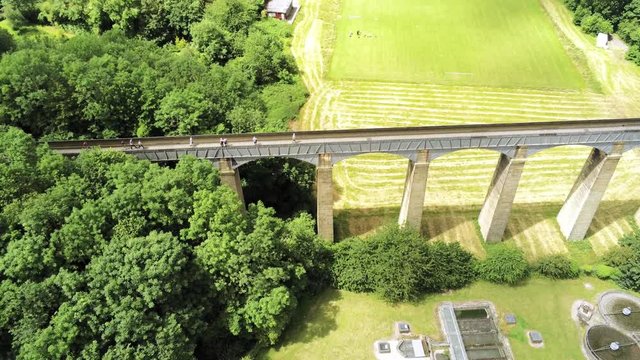 Pontcysyllte Aqueduct arch bridge canal waterway crossing. Rising tilt down aerial view above structure.
