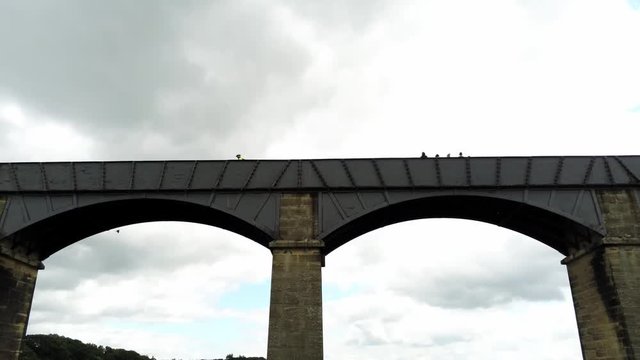 Pontcysyllte Aqueduct arch bridge canal waterway crossing. Close pull back aerial reveal across structure & countryside behind.