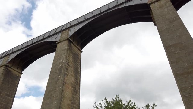 Pontcysyllte Aqueduct arch bridge canal waterway crossing. Push in slow dolly tilting up to view under arches.