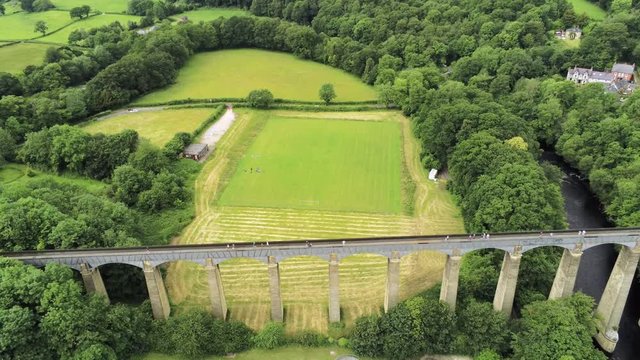 Pontcysyllte Aqueduct arch bridge canal waterway crossing. Descending aerial view above green landscape.