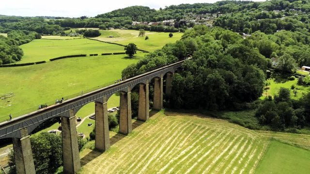 Pontcysyllte Aqueduct arch bridge canal waterway crossing. Fast aerial rotation away from landmark on sunny day.