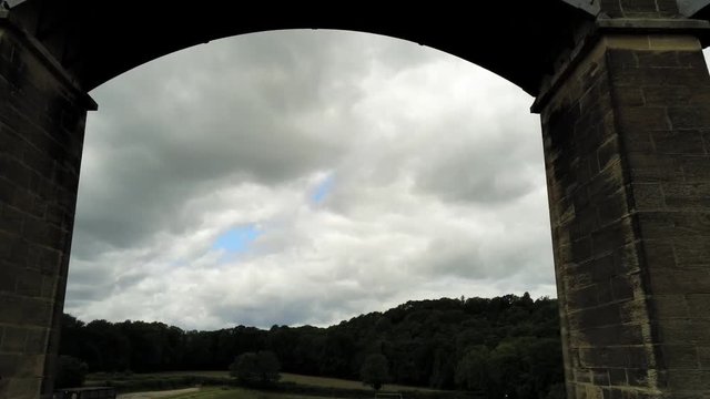 Pontcysyllte Aqueduct arch bridge canal waterway crossing. Aerial tilt up through arch under bridge.