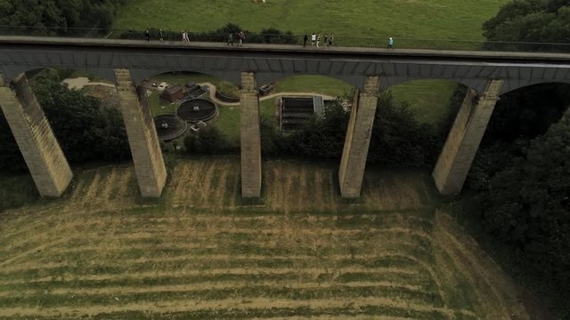 Pontcysyllte Aqueduct arch bridge canal waterway crossing. Ascending aerial moving over bridge & people crossing.