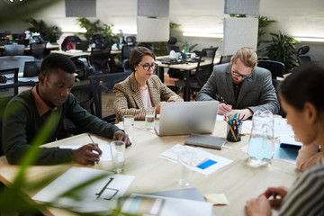 Multi-ethnic group of business people busy working during meeting in office, copy space