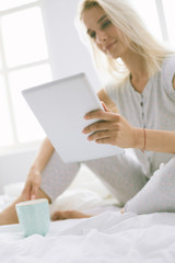 Girl holding digital tablet with blank screen and smiling at camera in bedroom