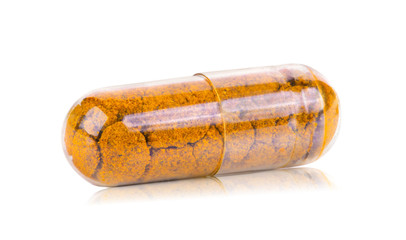 herb turmeric capsules spilling on white background