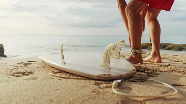 A man is standing with a surf in his hands on the sea shore.