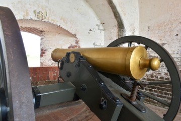 A brass US Civil War confederate canon sits abandoned at a historic fort.
