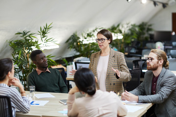 Portrait of successful female manager giving presentation during meeting with colleagues, copy space
