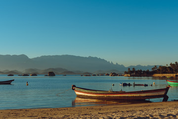 Sunset at Paqueta Beach in Rio de Janeiro with a boat in the foreground and mountains in the background