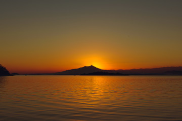 Fototapeta na wymiar Sunset at Paqueta Island in Rio de Janeiro with silhouettes of mountains on the horizon