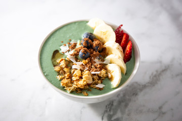 Spirulina yogurt with fruit in wooden bowl