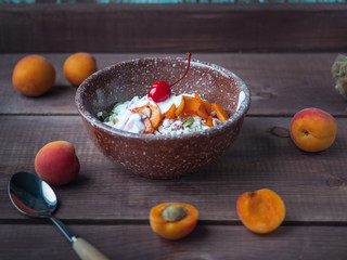 Breakfast of cottage cheese with fresh apricots in a deep ceramic plate on a wooden table