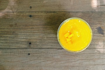 Refreshing Mango smoothie on wooden table with space on the left, top view.