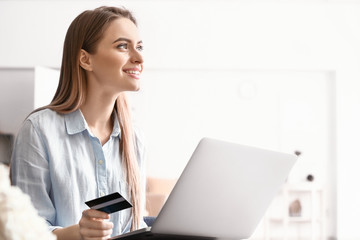 Young woman with credit card shopping online at home