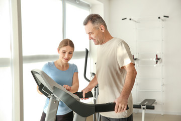 Fototapeta premium Physiotherapist working with mature patient in rehabilitation center