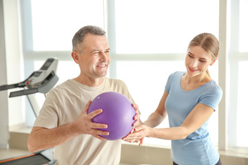 Physiotherapist working with mature patient in rehabilitation center