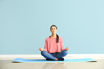 Fototapeta na wymiar Beautiful woman practicing yoga near color wall