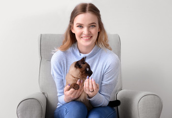 Young woman with cute Thai cat sitting in armchair