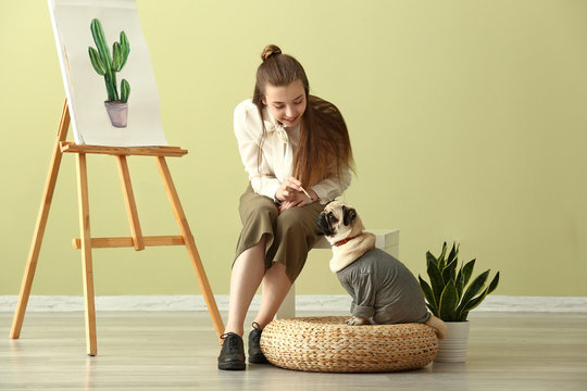 Teenage artist with cute pug dog at home