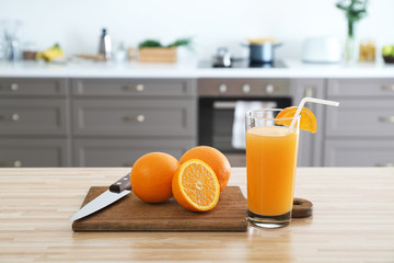 Obraz premium Cutting board with fresh oranges and juice in glass on table in kitchen