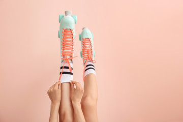 Legs of woman in vintage roller skates on color background