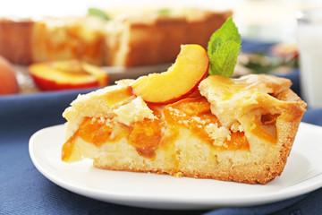 Plate with piece of tasty peach pie on table