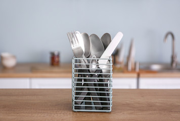 Clean cutlery in holder on table in kitchen