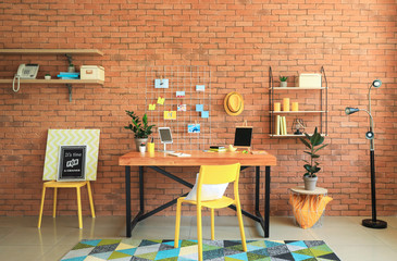 Workplace with mood board near brick wall in modern room